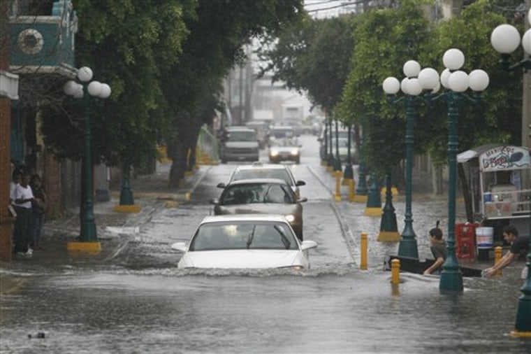 Drivers pass through a flooded street as children play in Nuevo Laredo, Mexico, Thursday, July 8, 2010. Police in both sides of the border were evacuating people in low-lying areas as the rain-swollen Rio Grande rose to more than 30 feet above flood stage and forced closure of two bridges linking Mexico and the U.S. (AP Photo/Miguel Tovar)
